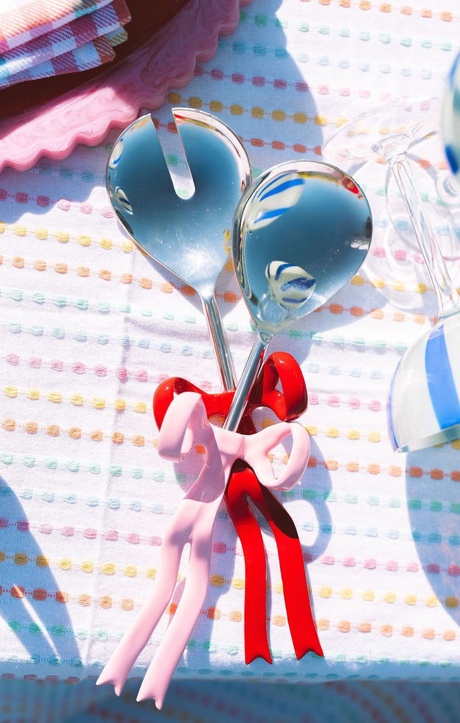Spoon and fork with blue handles and red ribbons on a colorful background