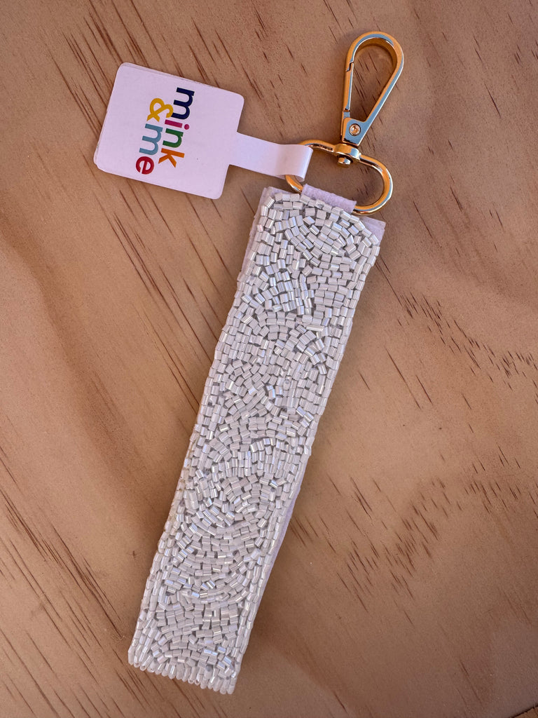 Keychain with textured strap and 'mink & me' tag on a wooden surface