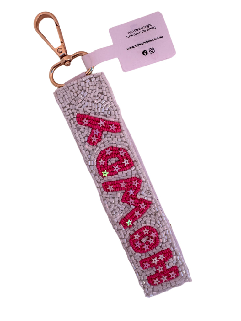 Keychain with 'howdy' text on a light pink background