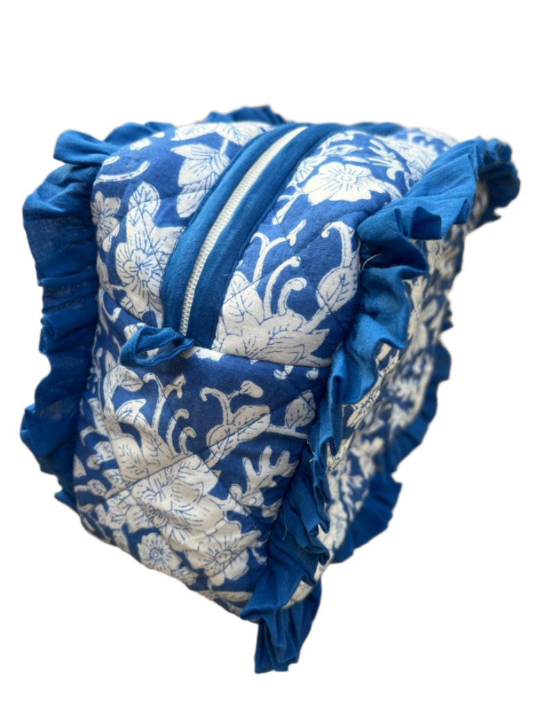 Blue and white floral-patterned bag with ruffles on a concrete surface