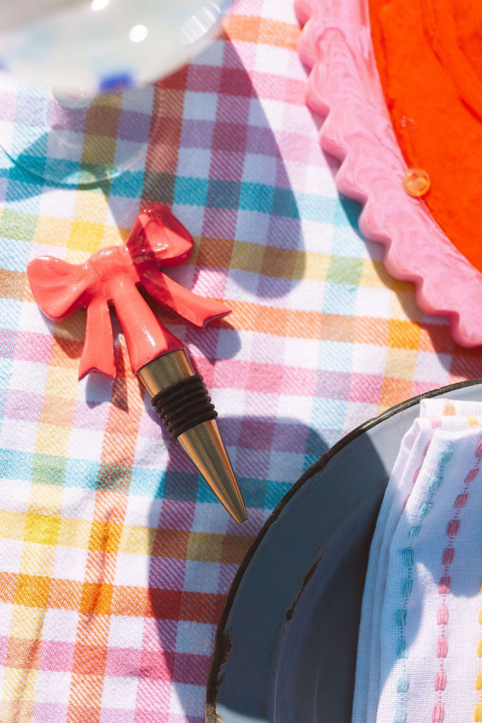 Bottle stopper with a decorative bow on a colorful checkered tablecloth