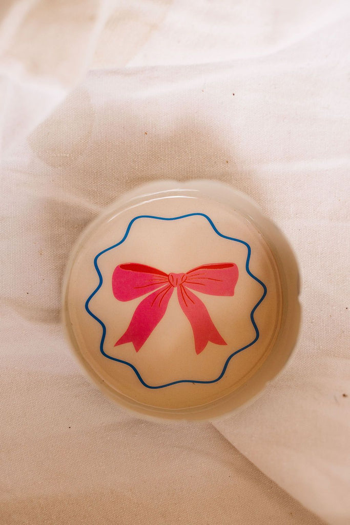 Round object with a pink bow design on a beige background