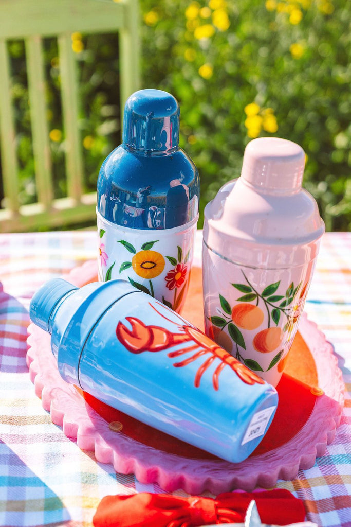 Three colorful bottles with decorative designs on a table outdoors.