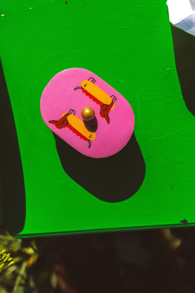 Pink button with cartoon characters on a green background