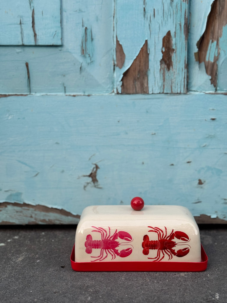 Butter dish with red lobster design on a worn wooden surface