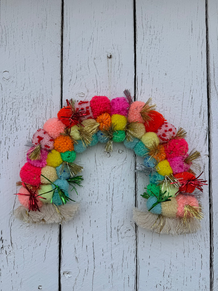 Colorful pom-pom rainbow on a wooden background