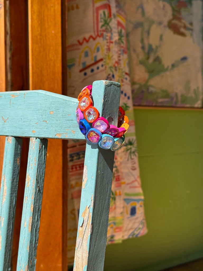 Colorful beaded bracelet on a wooden surface with a patterned fabric background