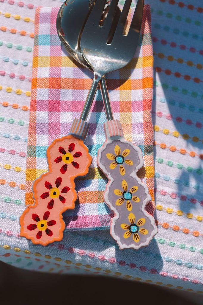 Decorative fork and spoon set with floral handles on a colorful checkered background